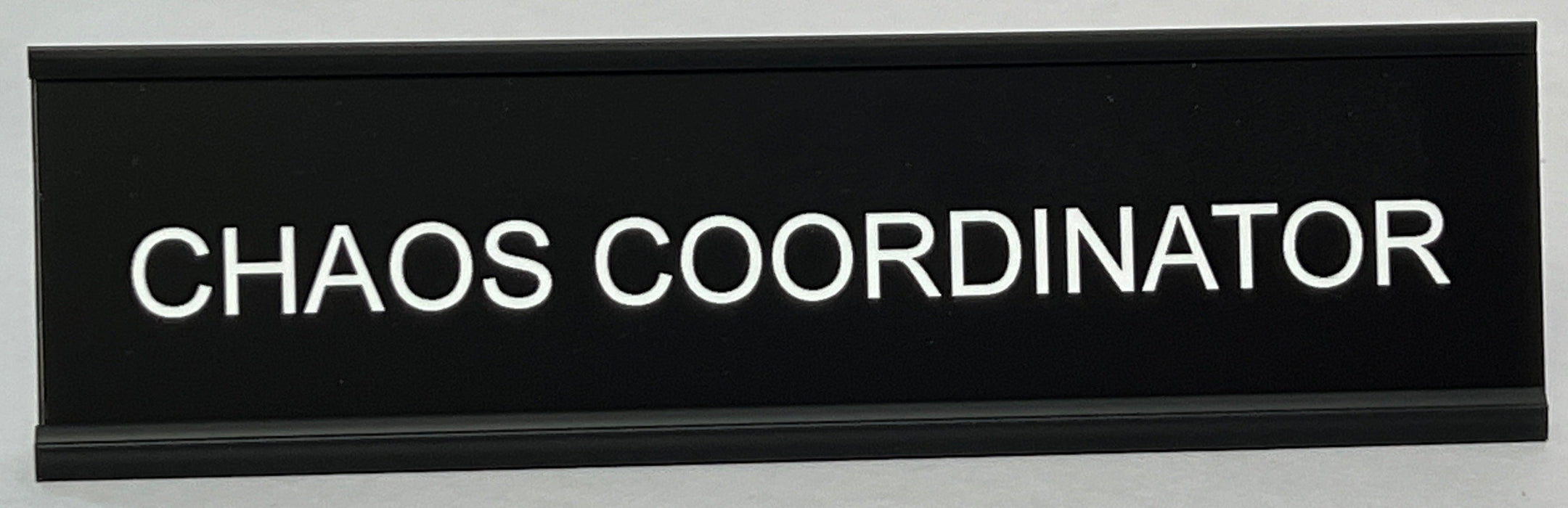 Black funny nameplate with 'CHAOS COORDINATOR' text on a white background