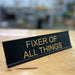 Fixer of all things desk sign sitting on top a dek in a warehouse.