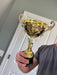 Lifestyle shot of gold trophy personalized with real metal cup trophy award.