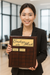 Woman holding an 'Employee of the Month' plaque in an office setting